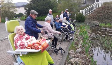 Zu sehen sind die Bewohnerinnen und Bewohner der Kurzzeitpflege vor dem Ententeich vor der Klinik.