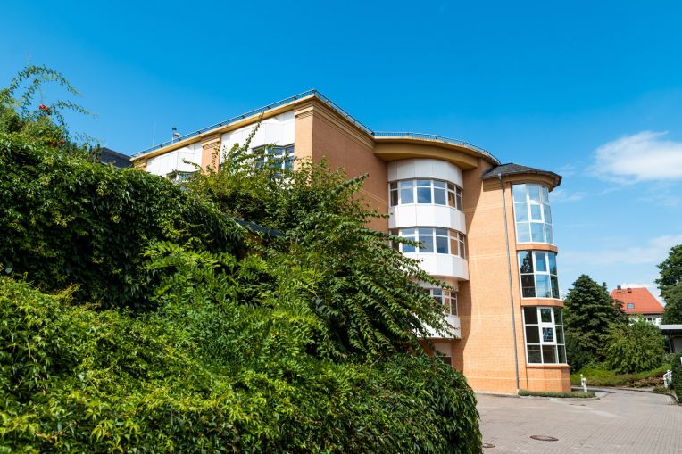 Zu sehen ist die Collm Klinik von außen mit Begrünung vor dem Gebäude.