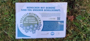 Zu sehen ist das Schild mit der Aufschrift "Menschen mit Demenz sind Teil unserer Gesellschaft."