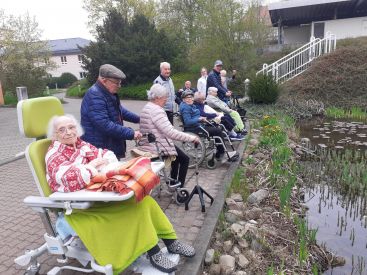 Zu sehen sind die Bewohnerinnen und Bewohner der Kurzzeitpflege vor dem Ententeich vor der Klinik.